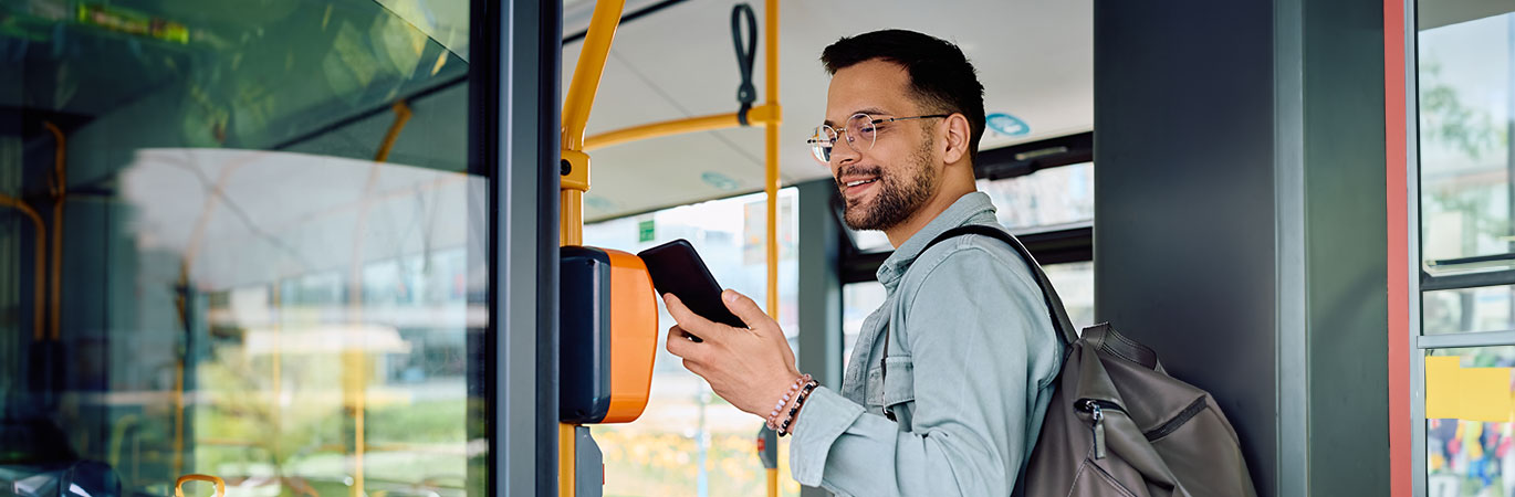 Mann steht vor einem Gebäude und lächelt während er auf sein Handy schaut